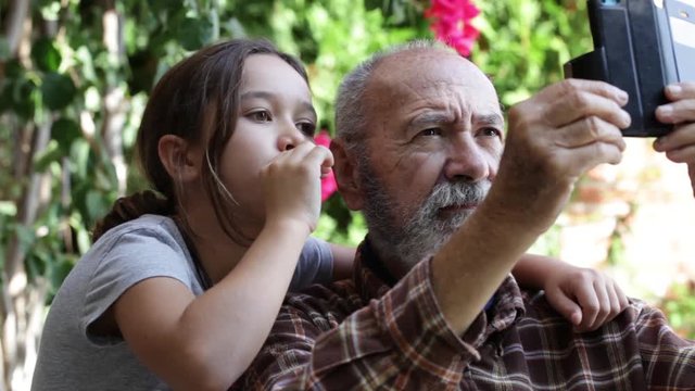 Abuelo y nieta mirando el m&oacute;vil