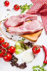 Two pork steak with meat knife and fork, fresh seasoning spices on dark rustic wooden background