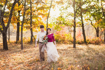 Stylish and romantic caucasian couple in the beautiful autumn park. Love, relationships, romance, happiness concept. Bouquet in girl's hands.