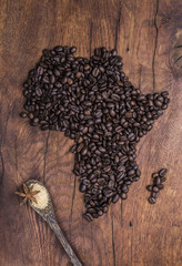 Roasted coffee beans arranged in the shape of Africa on old wood