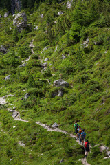 Group of Hikers walking on a mountain trail in vall di Funes, Dolomite Alps, Northern Italy