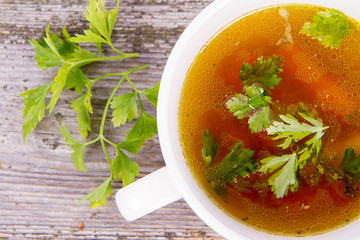 Chicken soup with carrots and parsley on wooden background