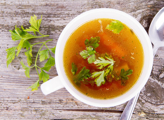 Chicken soup with carrots and parsley on wooden background