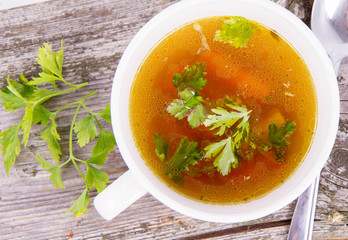 Chicken soup with carrots and parsley on wooden background