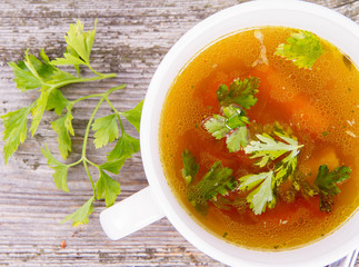 Chicken soup with carrots and parsley on wooden background