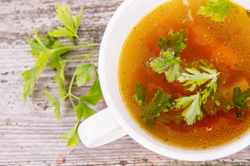 Chicken soup with carrots and parsley on wooden background