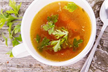 Chicken soup with carrots and parsley on wooden background