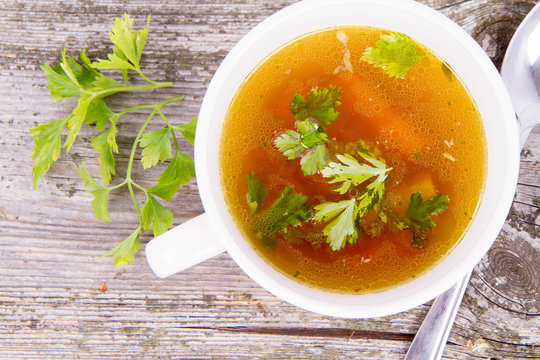 Chicken soup with carrots and parsley on wooden background