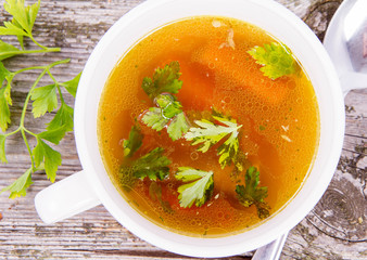 Chicken soup with carrots and parsley on wooden background