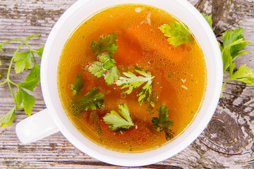 Chicken soup with carrots and parsley on wooden background