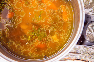 Chicken soup with carrots and parsley in a pot