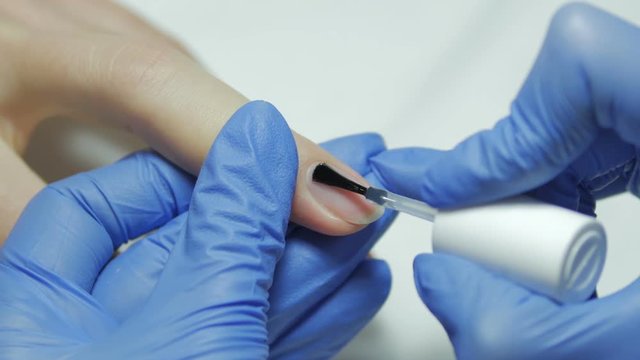 Manicurist covers the nail base gel polish