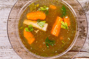 Chicken soup with carrots and parsley on wooden background