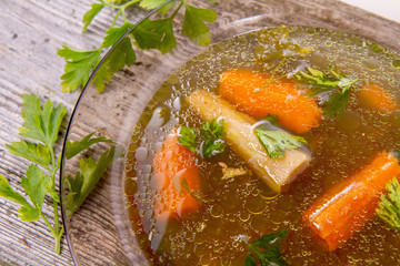 Chicken soup with carrots and parsley on wooden background