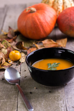 Autumn pumpkin soup on natural wooden table.
