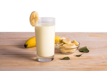 Banana cocktail, banana slices in a bowl. On a wooden background.