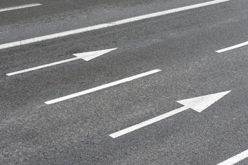 two white arrows signs on an urban asphalt road