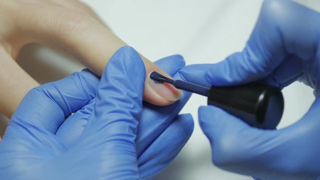 Manicurist covers blue gel nails polish