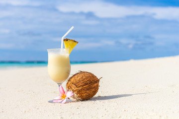 Pina Colada cocktail on the beach with coconut and exotic flower