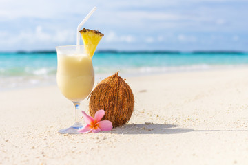 Pina Colada cocktail on the beach with coconut and exotic flower - obrazy, fototapety, plakaty