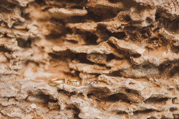 wedding rings and engagement ring on the background of textured rock