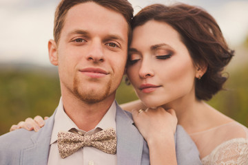 Romantic and stylish caucasian couple standing in the beautiful vineyard at sunset. Love, relationships, romance, happiness concept.