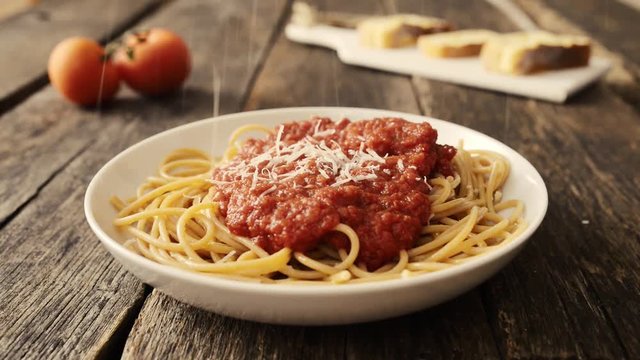 Putting parmesan cheese on spaghetti with tomato sauce