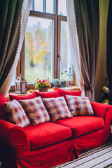 Daybed with cushions in rustic home. on the table bouquet of flowers and a candlestick pumpkin