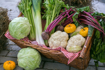 fall vegetables in a wicker basket on a wooden background haystacks