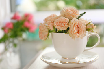 Bouquet of beautiful roses in a cup on a  table