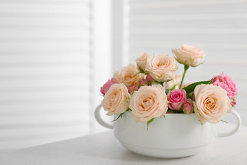 Bouquet of beautiful roses in a cup on a  table