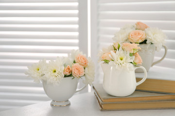 Bouquet of beautiful roses in  cups on books