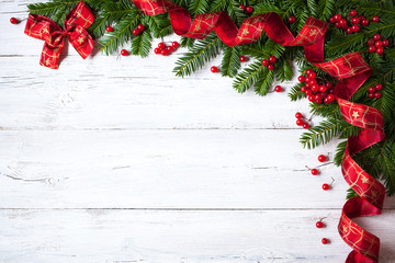 Christmas wooden background with branches of trees, berries and red ribbon