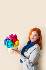 A woman holding a basket of white skeins of wool for felting. 