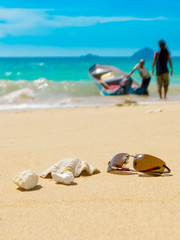 Fototapeta na wymiar Sunglasses shell coral reef on sandy beach, incoming boat landin