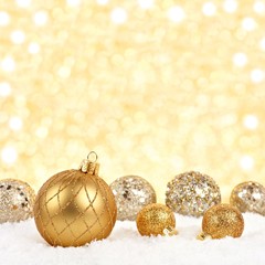 Golden Christmas ornaments in snow with twinkling gold background