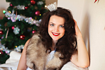 Happy woman in festive dress in front of Christmas tree