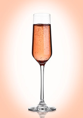 Glass of pink rose champagne with bubbles on pink