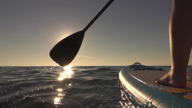 CLOSE UP: Detail of paddling stand up paddleboard through glittering ocean water