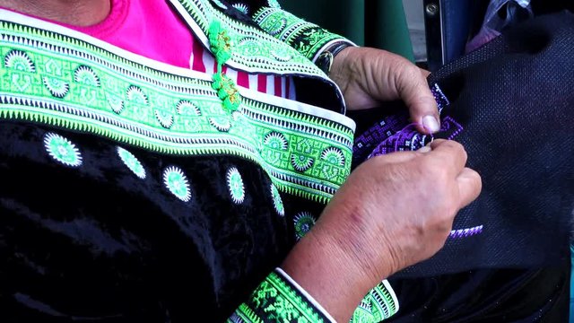 Close-up female hand of Hmong hilltribe embroider pattern colored thread.