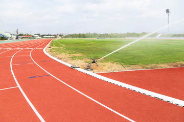 sprinkler and water hose in grass field football stadium 