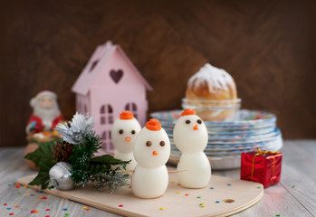 New Year. Snowmen made of chicken eggs and are on the holiday table. A dish of eggs to meet the new year. Snowman is the symbol of winter. Table layout.