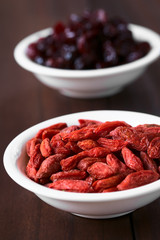 Dried gojis or wolfberries in small bowl with dried cranberries in the back, photographed with natural light (Selective Focus, Focus one third into  the image)