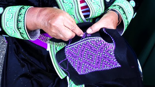 Close-up female hand of Hmong hilltribe embroider pattern colored thread.