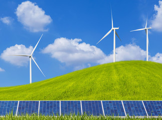 photovoltaics solar panels and  wind turbines generating electricity on grass hill and blue sky...