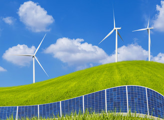 photovoltaics solar panels and  wind turbines generating electricity on grass hill and blue sky with clouds.Ecology green nature concept.