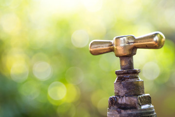 Brass water tap in nature background.