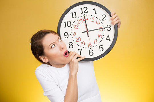 Stressed woman holding clock looking anxiously running out of time