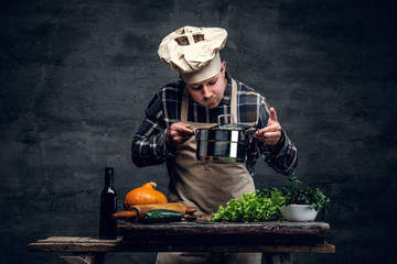 A man cooking a soup and tasting it.