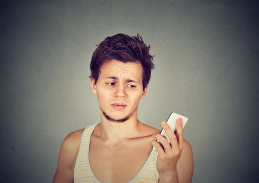 annoyed man holding cellphone looking mad at stressful texts